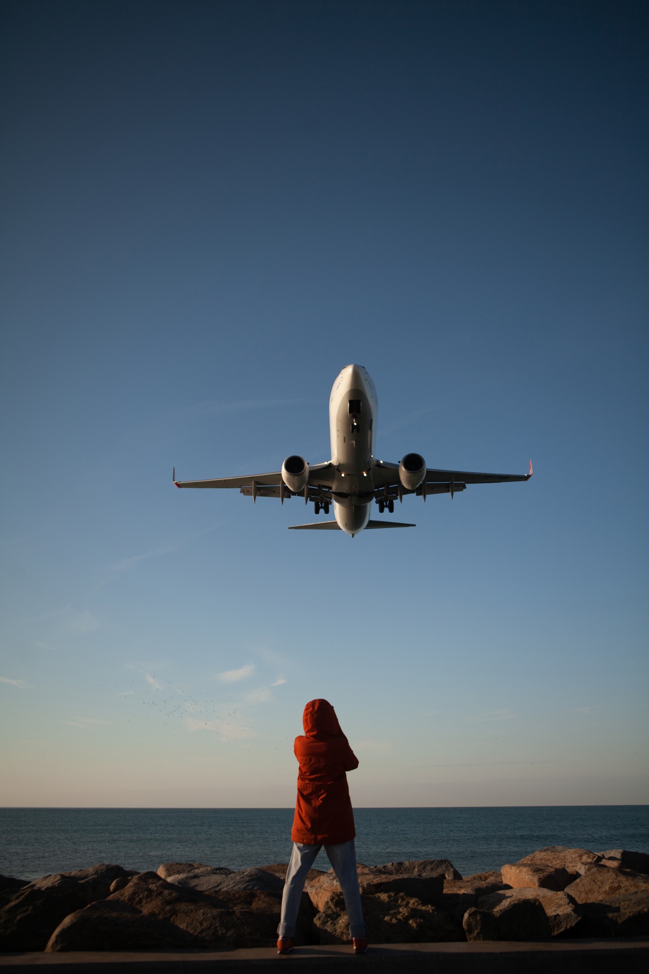 the girl taking photo of the plane coming in for landing